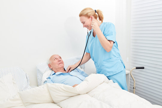 Krankenschwester mit Stethoskop hört Patient ab