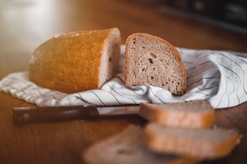 Rustic crusty loaves of bread on wooden plate. Bakery concept with cut sliced homemade bread. Sliced bread on a wooden cutting board.