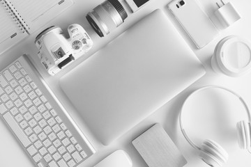 Flat lay of white office desk table with many white gadgets