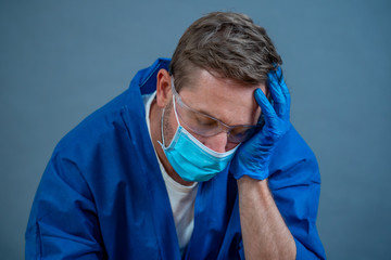 Male doctor feeling exhausted after long shift treating coronavirus infected patients at hospital