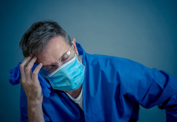 Male doctor feeling exhausted after long shift treating coronavirus infected patients at hospital