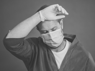 Male doctor feeling exhausted after long shift treating coronavirus infected patients at hospital