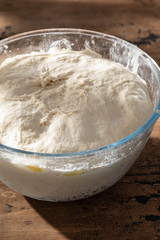 Bowl of fresh raw dough on wooden background.