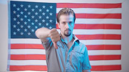 Man in front of American flag gives thumbs down