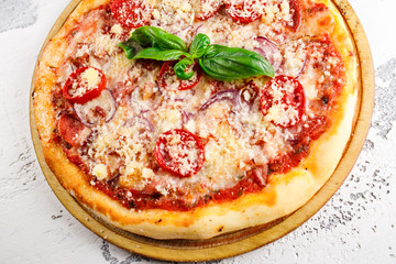 mini pizza margherita with parmesan basil and tomatoes on a wooden plank close-up on a white texture background