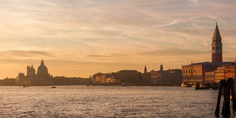Fototapeta premium Venice Lagoon with St Mark Square famous monument, Salute Basilica dome and beautiful sunset colors and evening haze