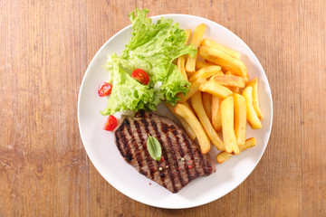 plate of beefsteak,french fries and lettuce