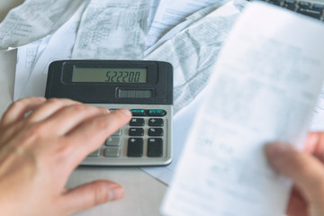 Woman uses a calculator to sum up expenses
