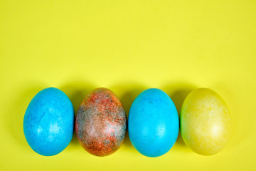 Multicolored, painted Easter eggs on a yellow background. space for text