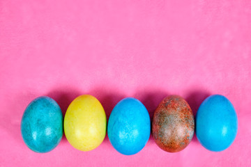 Multicolored, painted Easter eggs on a pink background. space for text
