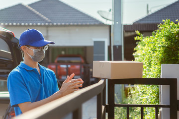 Asian Delivery man wearing mask send a package applying hand spray alcohol cleaning on before deliver cargo social distancing while the virus is spreading, Clean washing hands for protect covid-19.