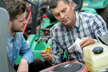 portrait of men repairing lawn mower engine