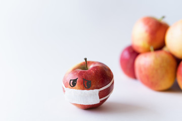Red apple wearing medical mask isolated from the crowd. Conceptual image of social distancing during Corona virus quarantine