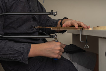 a man sawing a wooden detail with a jigsaw, closeup hands. wood cutting at home