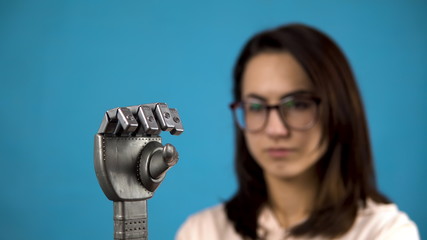 A young woman looks at her mechanical arm. Cyborg arm on a gray hand on a blue background.
