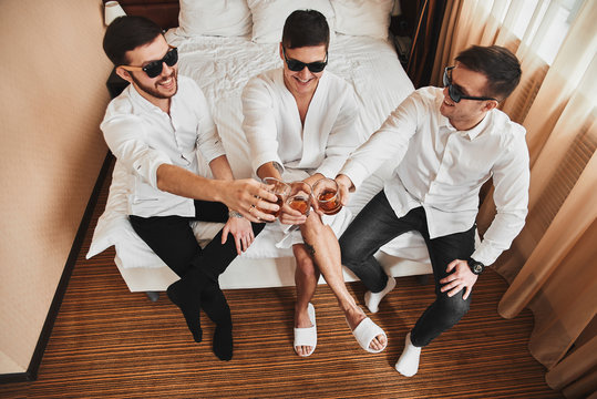 The groom is going to the wedding. Photosession of three energetic guys at the hotel. Brown tones.