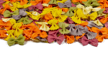Fototapeta premium Italian raw multicolored farfalle pasta on white background with copy space. Colorful pasta in bow tie shape. Italian cuisine concept. Mockup for design.