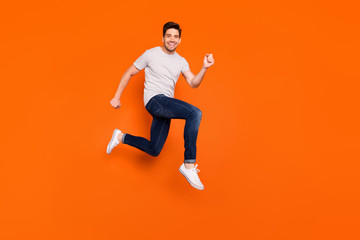 Fototapeta na wymiar Full body profile photo of attractive crazy jump high rush shopping center addicted shopper discounts wear striped t-shirt jeans shoes isolated bright orange color background
