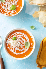 Pumpkin and carrot soup with cream and basilic on blue stone background Top view
