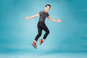 Fototapeta na wymiar Hnadsome Asian man jumping isolated over blue wall background. 