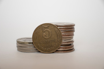 a coin worth five kopeks of the USSR stot vertically next to piled coins.