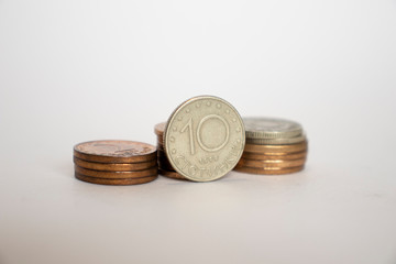Bulgarian stotinka coin stands vertically next to other coins piled in a stack. coins on a white background. money of bulgaria