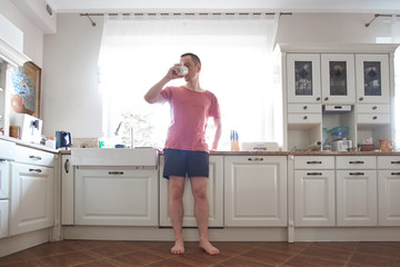 Fototapeta na wymiar Attractive young caucasian man drinking tea or coffee in morning at home. Good morning.