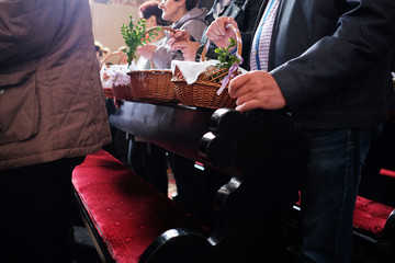 People holding easter baskets with eggs in the church.