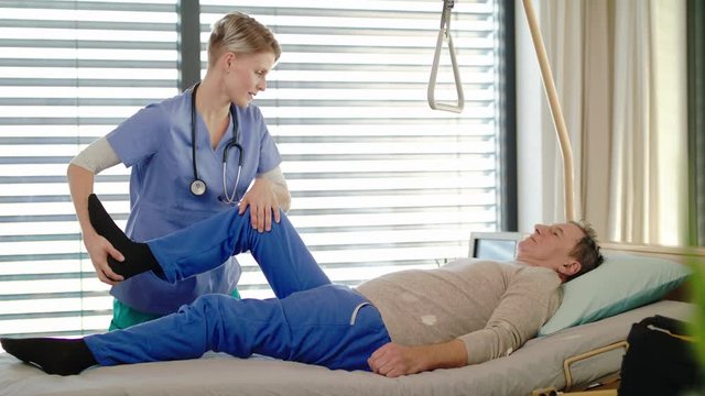 Healthcare worker and paralysed senior patient in hospital, physiotherapy.
