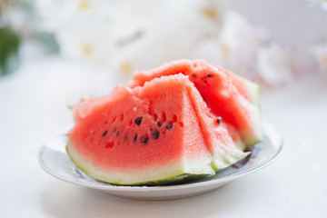 sliced juicy watermelon on a plate on a white blurred background