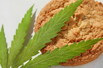 Cookies are close-up with the content of CBD cannabidiol. Cookies with hemp or cannabis with a green marijuana leaf. Treatment of medical marijuana for use in food, use CBD
