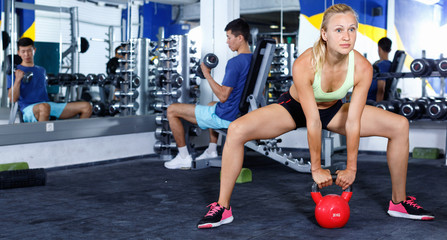 Concentrated athletic girl during workout in gym with dumbbells
