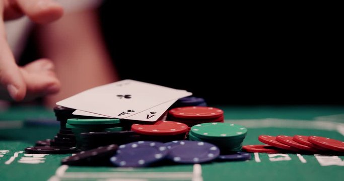 Close up of gambler throwing pocket rockets two aces on a heap of chips in the middle of poker table shot in 4k super slow motion