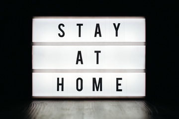 Close-up of lightbox with Stay at home text on black background. Stay home social media campaign for coronavirus or COVID-19 prevention. Quarantine and self isolation concept