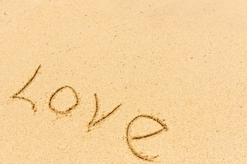 Close up love sign and wave on a sandy beach. Background close up.