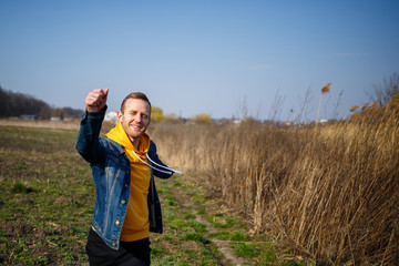 Naklejka na ściany i meble Smiling man enjoying wind blowing in forest. Happy man feeling joy while walking at nature, free space on green trees background. Life love, joy, fresh air, renovation concept