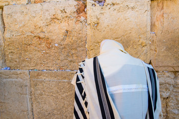 Orthodox Jew praying at the Western Wall, wearing the tallit prayer shawl