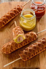 Waffle corn dogs served with jars of mustard and ketchup