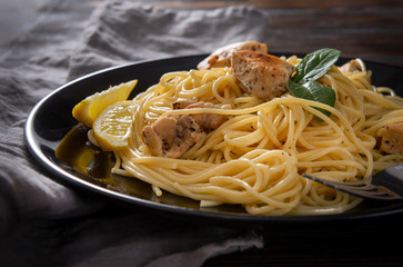 pasta spaghetti   with chicken fillet,  on a black plate, napkin,  on a dark wooden background