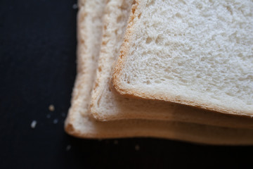 A close up of 3 slices of white bread against a black background