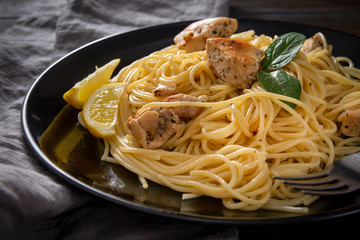 spaghetti   with chicken   on a black plate , napkin,  on a dark wooden background, hot pasta