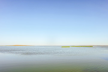 Calm water surface with clear blue sky. Akhtanizovsky estuary water landscape. Krasnodar region, Russia.