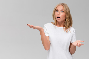 Studio portrait of cute puzzled hesitant young woman shrugs shoulders, does not know what happened. Pretty attractive woman doubting isolated on gray background