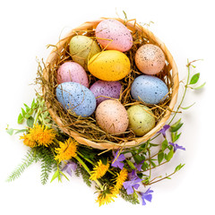 Easter. Congratulations on the spring holiday of Easter. Multi-colored eggs in a basket decorated with flowers. Isolate on white background
