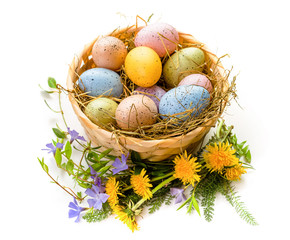 Easter. Congratulations on the spring holiday of Easter. Multi-colored eggs in a basket decorated with flowers. Isolate on white background