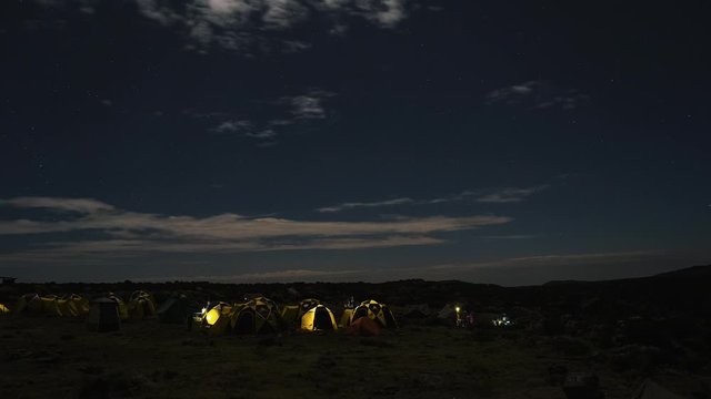 Pitched tents camping at the base of Mount Kilimanjaro. Beautiful timelapse view of the clouds moving over the tents.