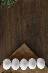 Easter natural eggs line on brown wooden background and sackcloth. Vertical 