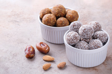 Two bowls of homemade raw chocolate and lemon energy balls, some almond and dates. Healthy vegan and vegetarian food