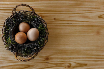 Easter natural eggs in basket on yellow natural wooden background. Left side