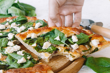 Pizza with spinach on a white background. Diet Pizza. Proper nutrition. Hand takes pizza